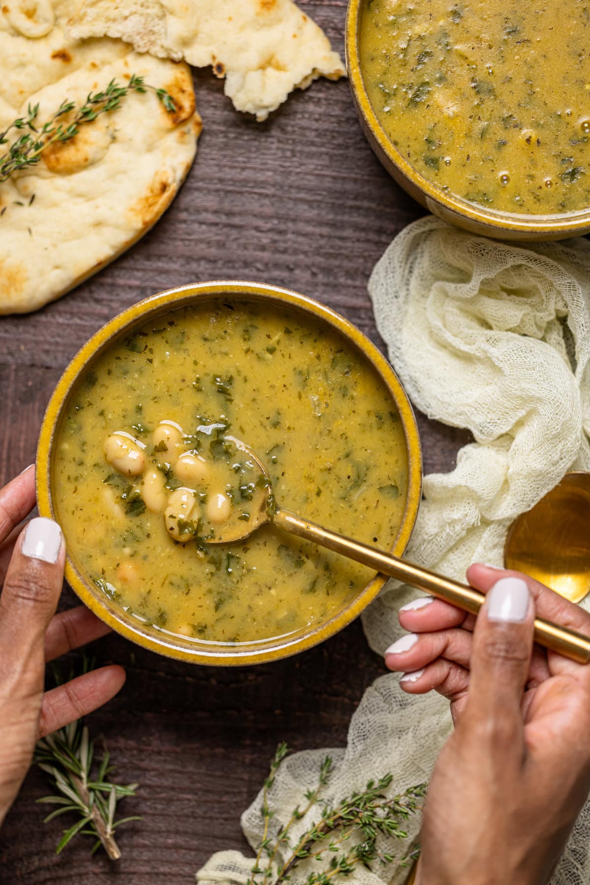 Hand dipping a spoon into a bowl of Creamy Vegan White Bean Soup 