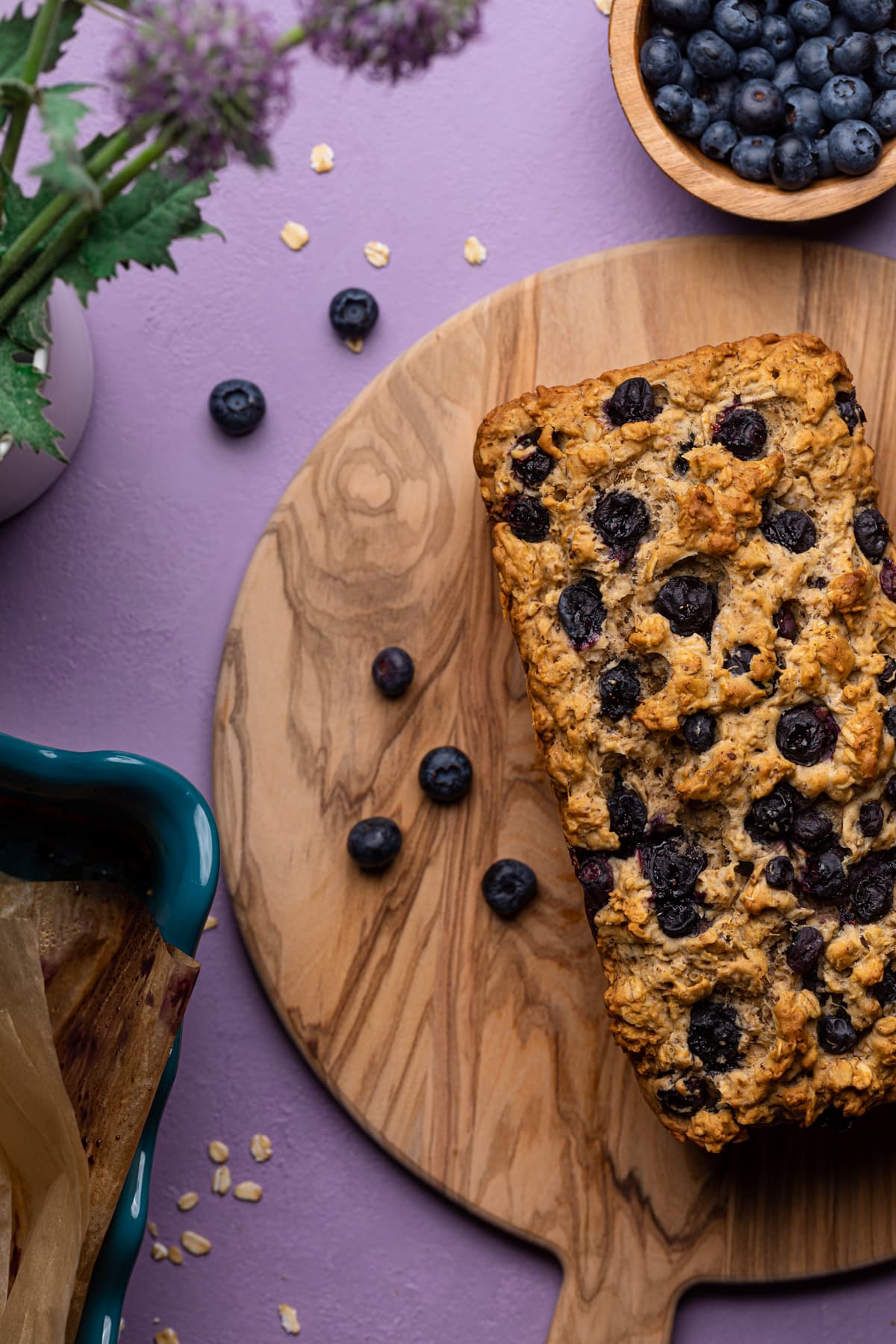 Blueberry Oatmeal Breakfast Bread with fresh berries on a cutting board.