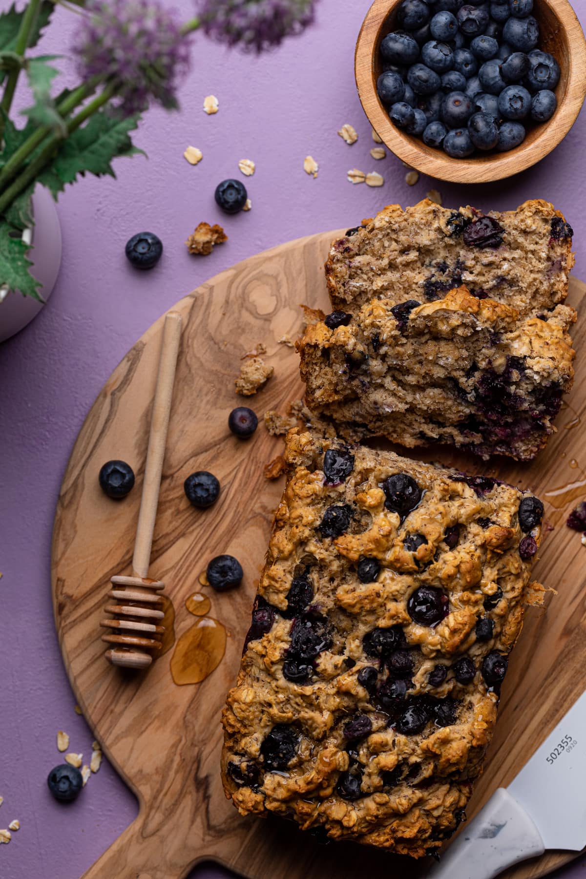 Blueberry Oatmeal Breakfast Bread cut into slices with fresh blueberries.