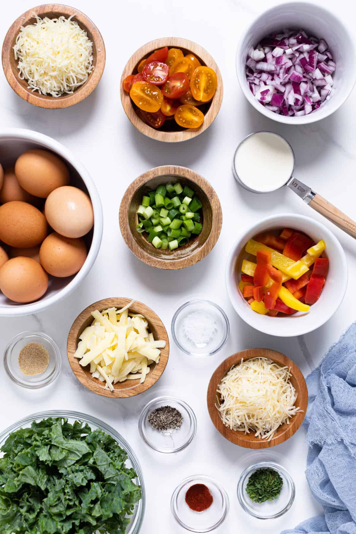 Bowls of frittata ingredients including red onions, tomatoes, and pepper.