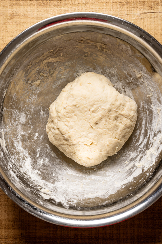 Pizza dough in a silver bowl.