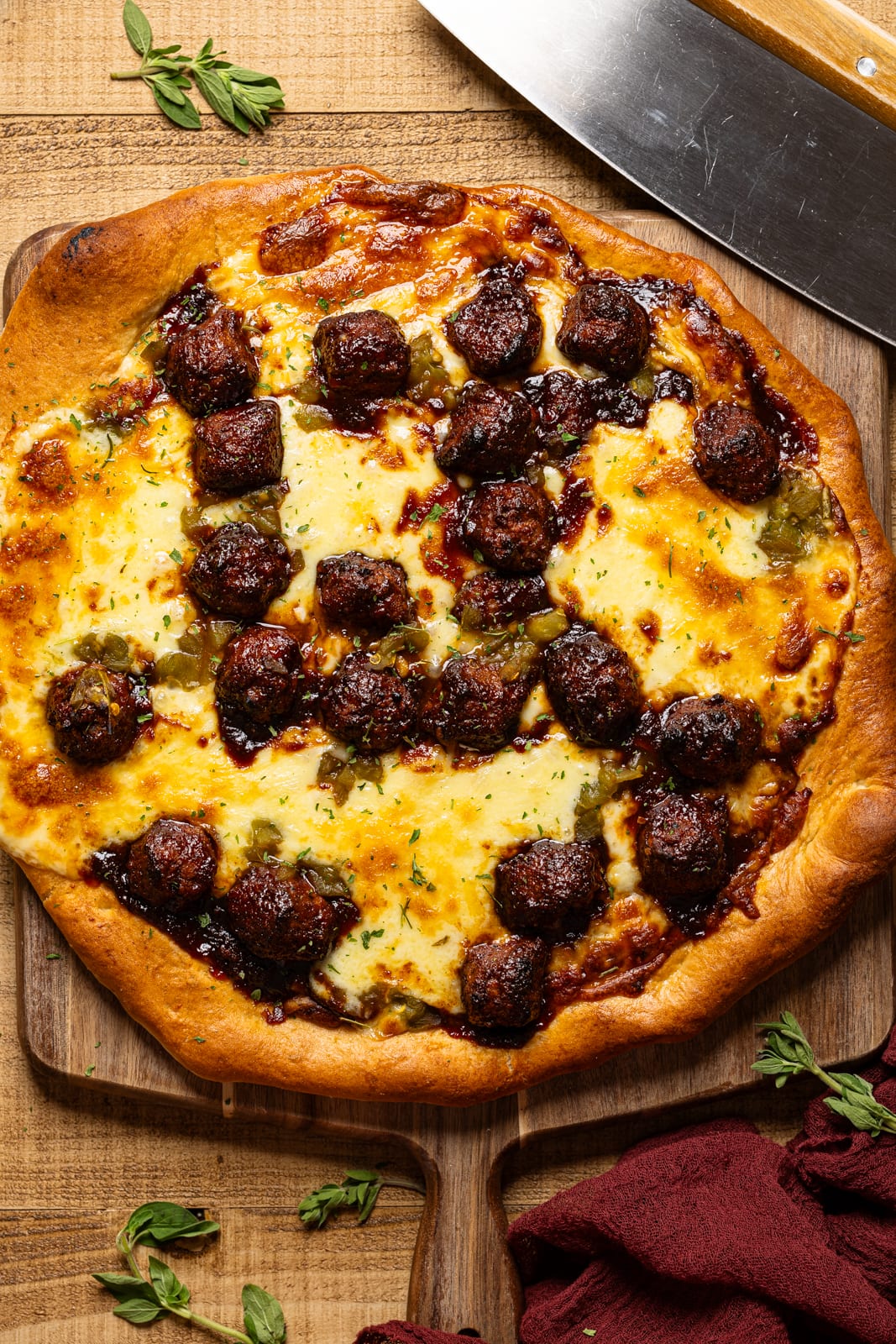 Baked pizza atop a board with a cutting knife.