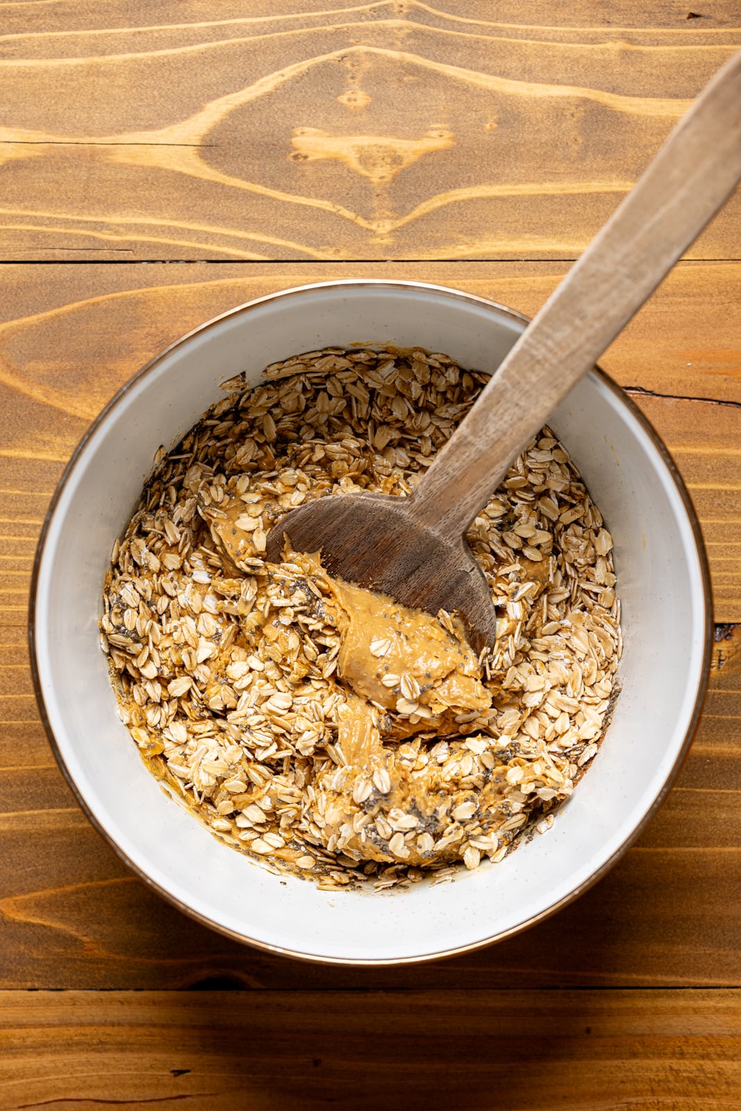 All ingredients mixed together in a large white bowl with a wooden spoon.