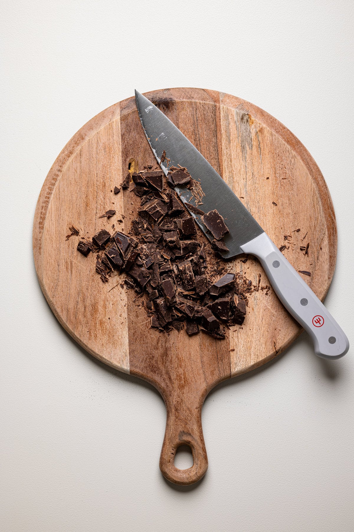 Crushed chocolate and a knife on a wooden cutting board.