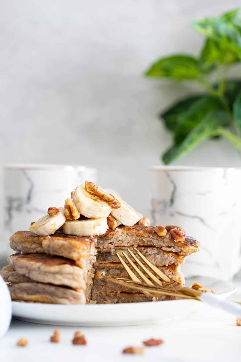 Vegan Banana Bread Pancakes on a plate with golden silverware.