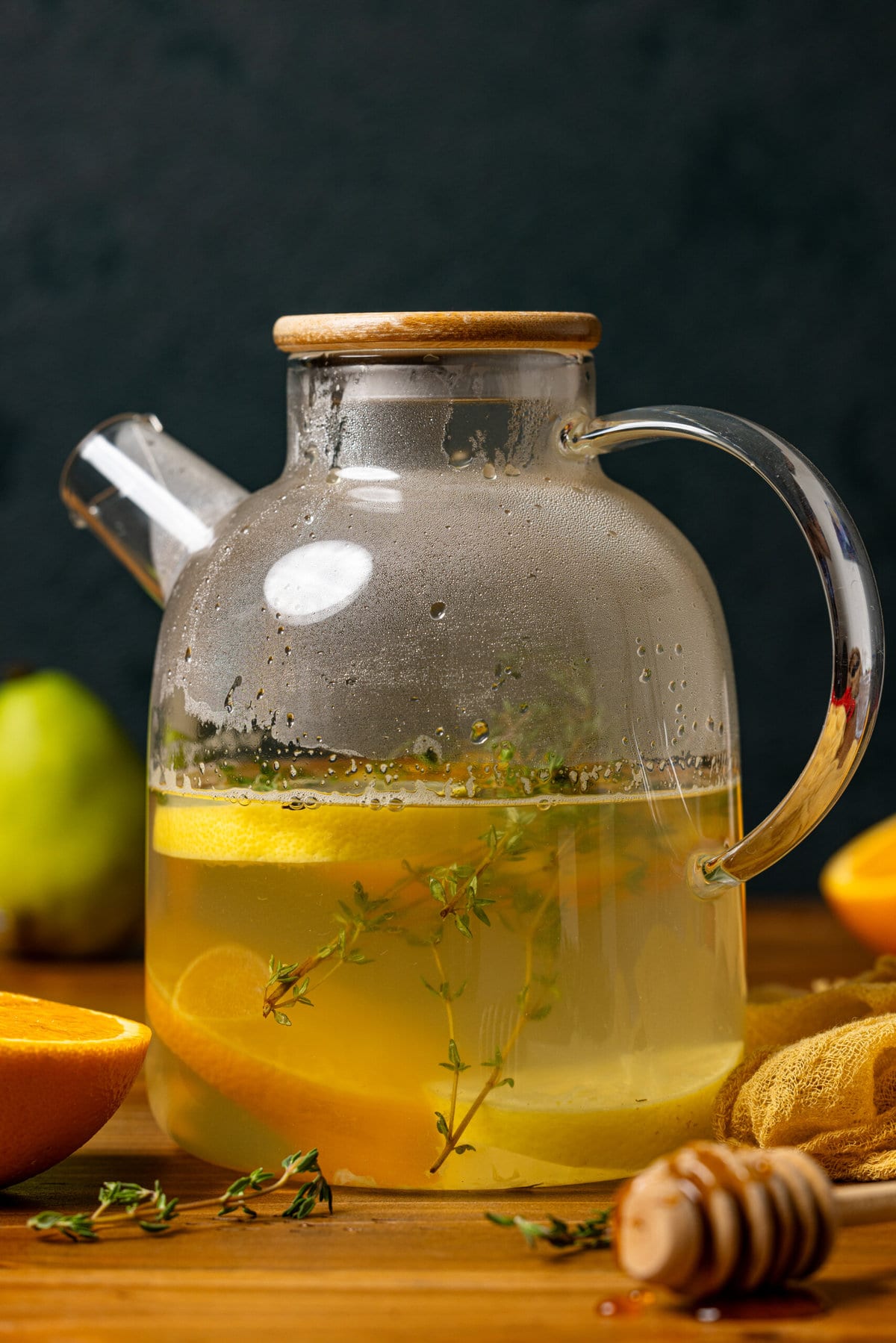 Healthy Detox tea in a tea pot on a brown wood table with orange and pears.