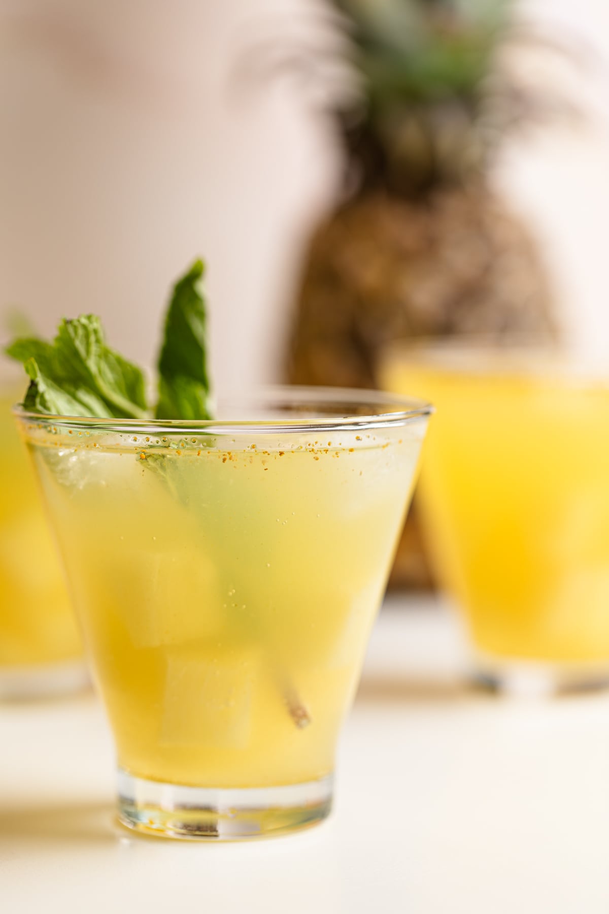 Three glasses of Pineapple Ginger Turmeric Lemonade on a table.