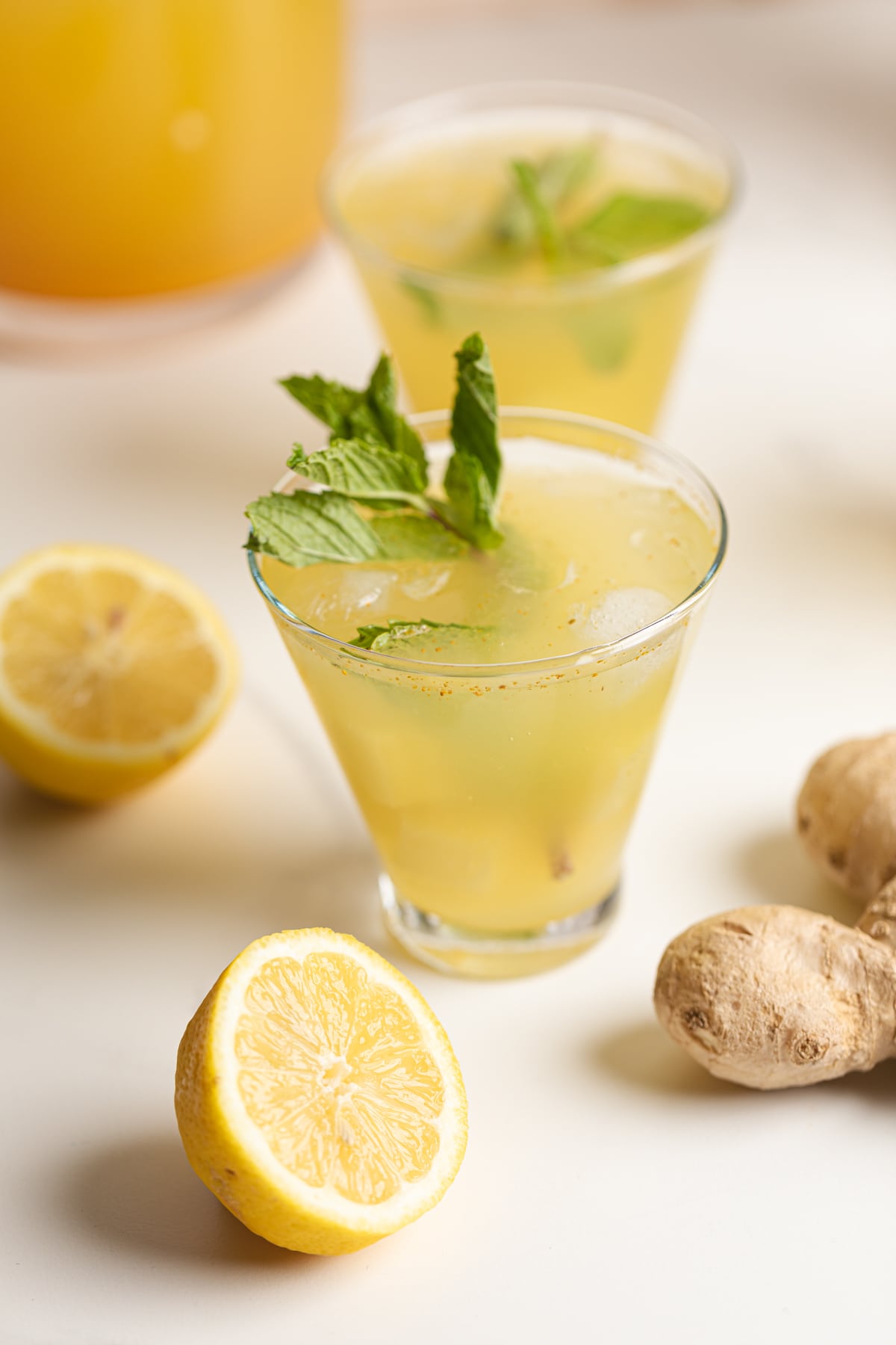 Glass of Pineapple Ginger Turmeric Lemonade on a table with ginger and lemons.