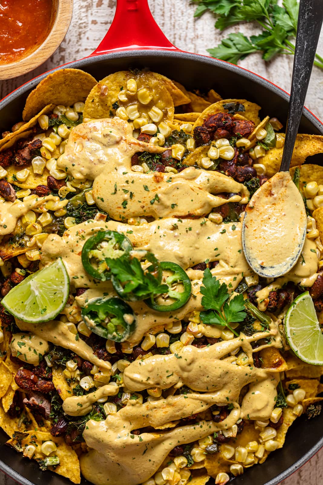 Closeup of a spoon in Loaded Vegan Queso Skillet Nachos