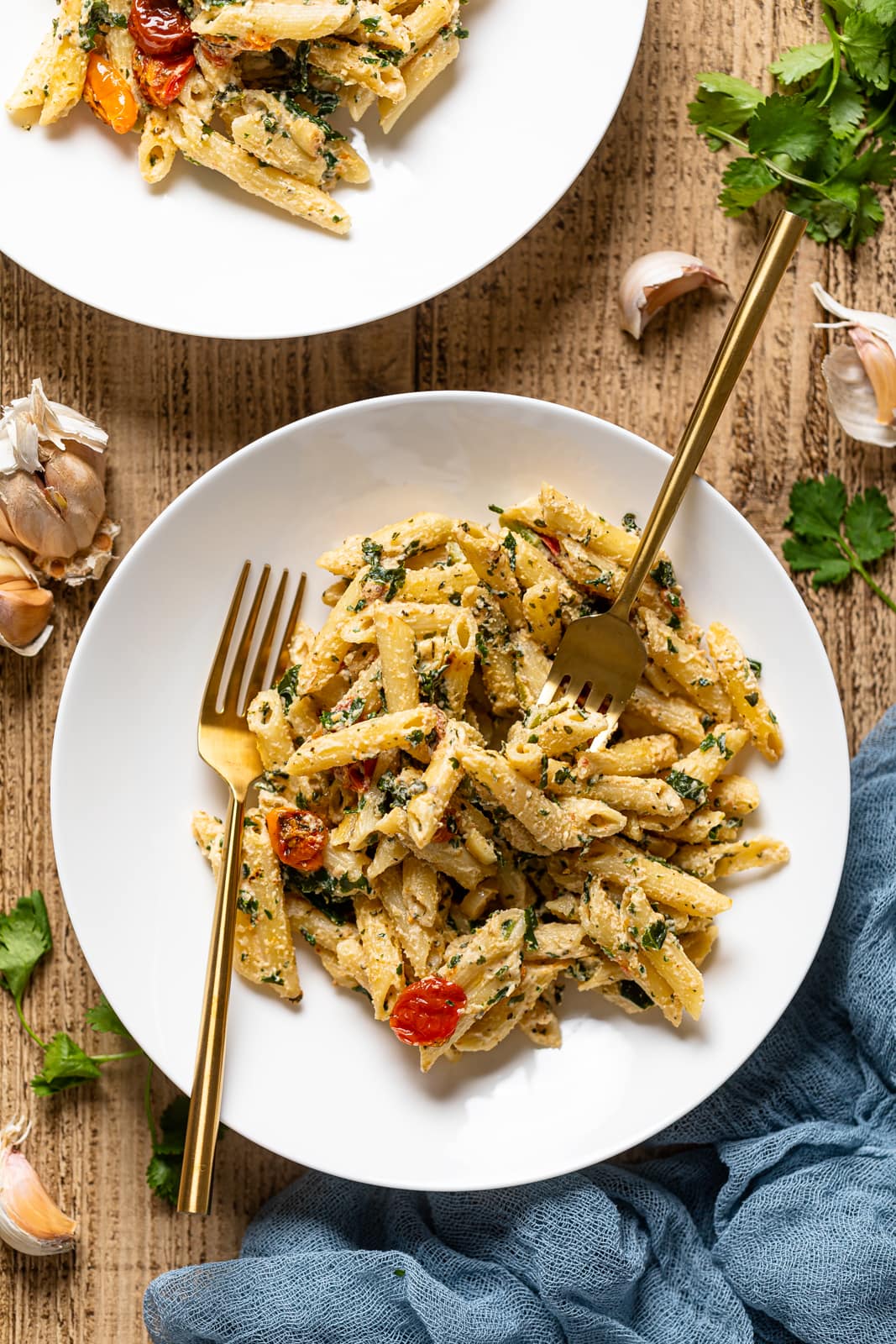 Overhead shot of a plate of Creamy Vegan Tuscan Kale Pasta with two forks