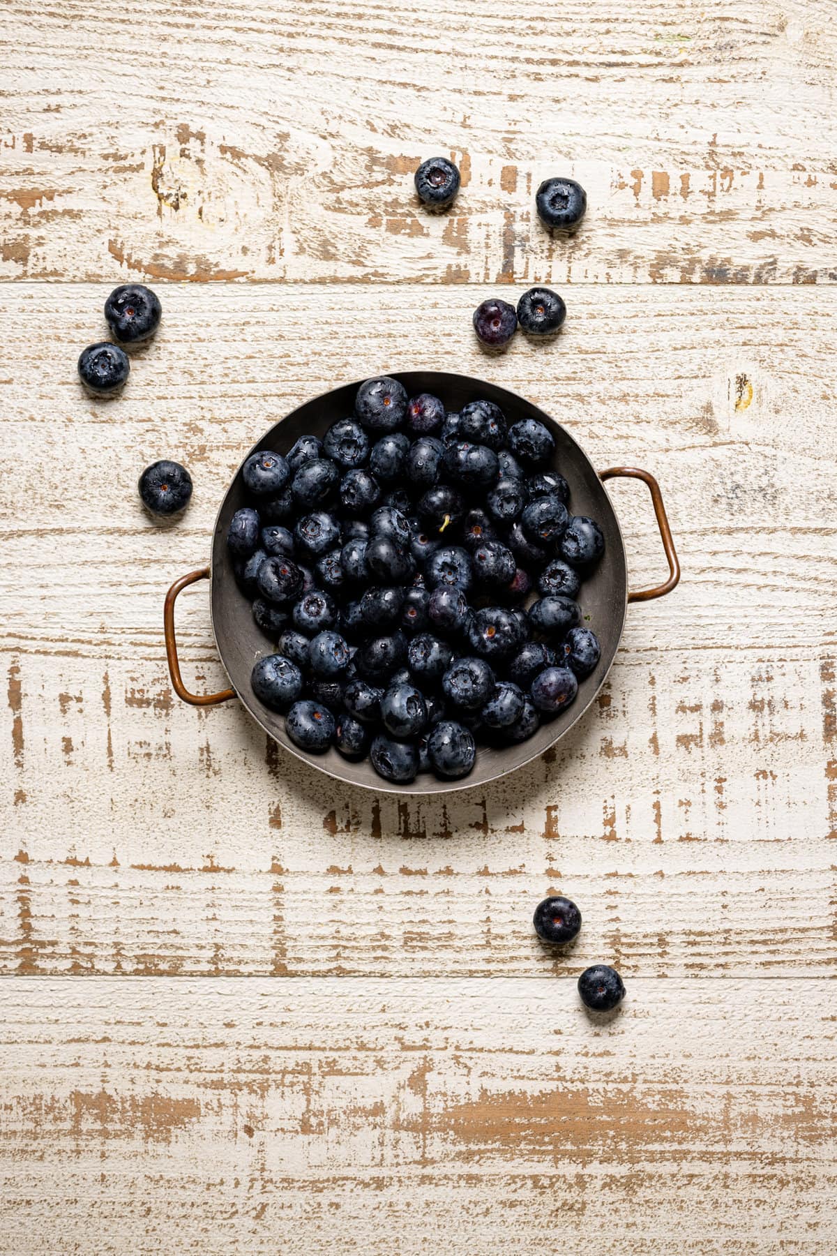 Bowl of blueberries on a white, wooden table.