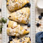Dairy-Free Blueberry Almond Scones on a plate with blueberries and slivered almonds.