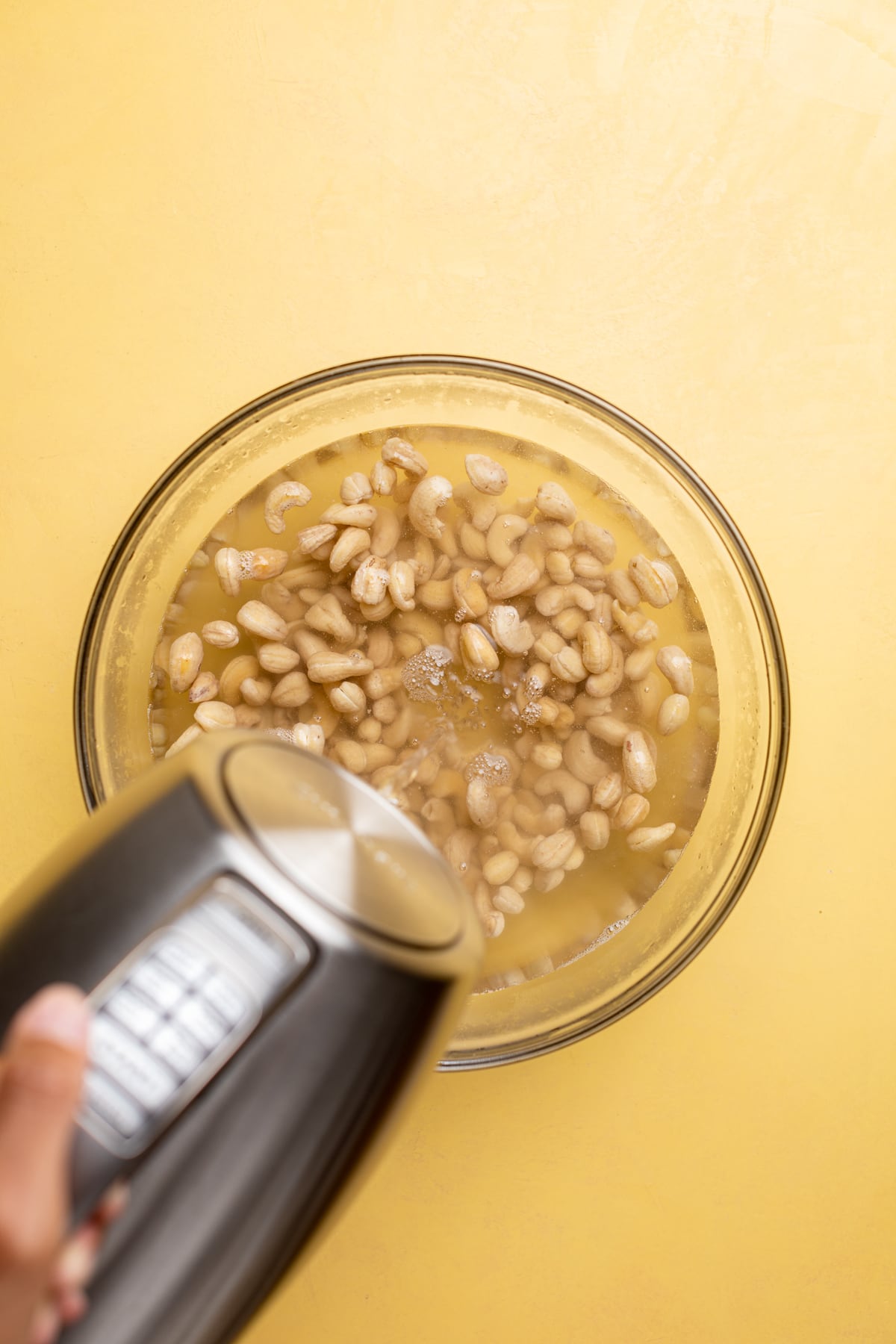 Water pouring into a bowl of cashews