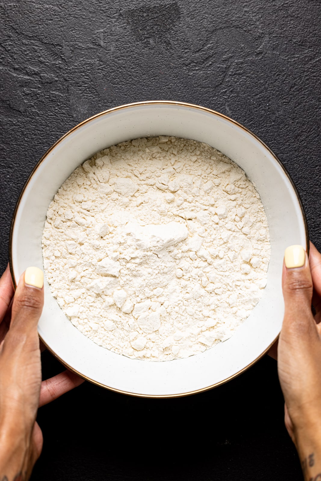 Flour in a white bowl on a black table.