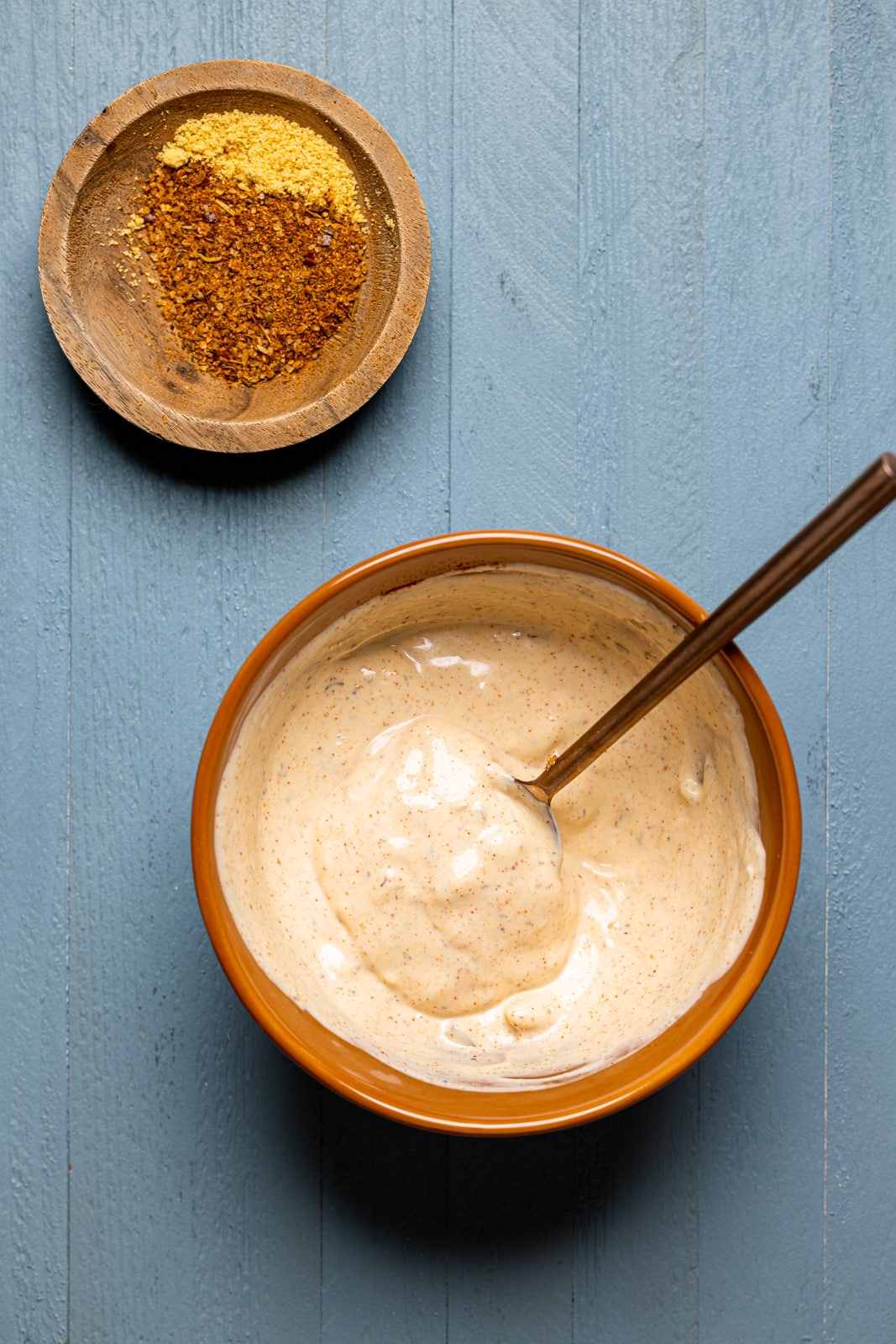 Po\' Boy sauce in a bowl and seasonings on a blue wood table.