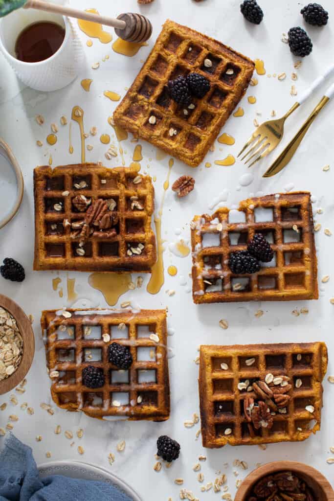 Flourless Vegan Sweet Potato Oats Waffles on a counter drizzled with syrup.