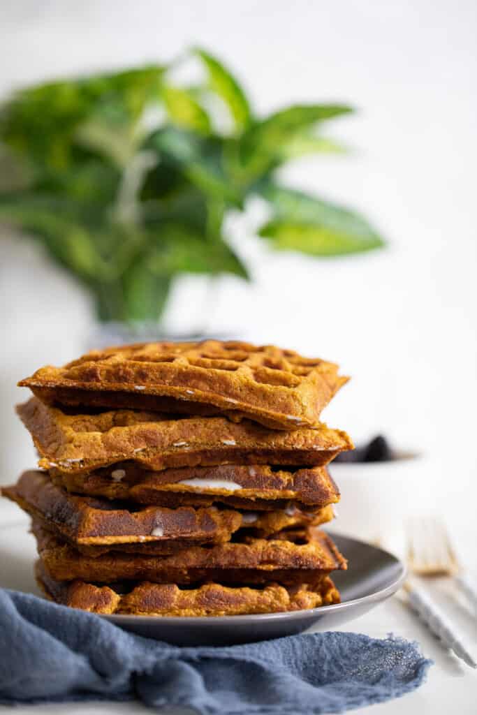 Stack of Flourless Vegan Sweet Potato Oats Waffles on a grey plate.