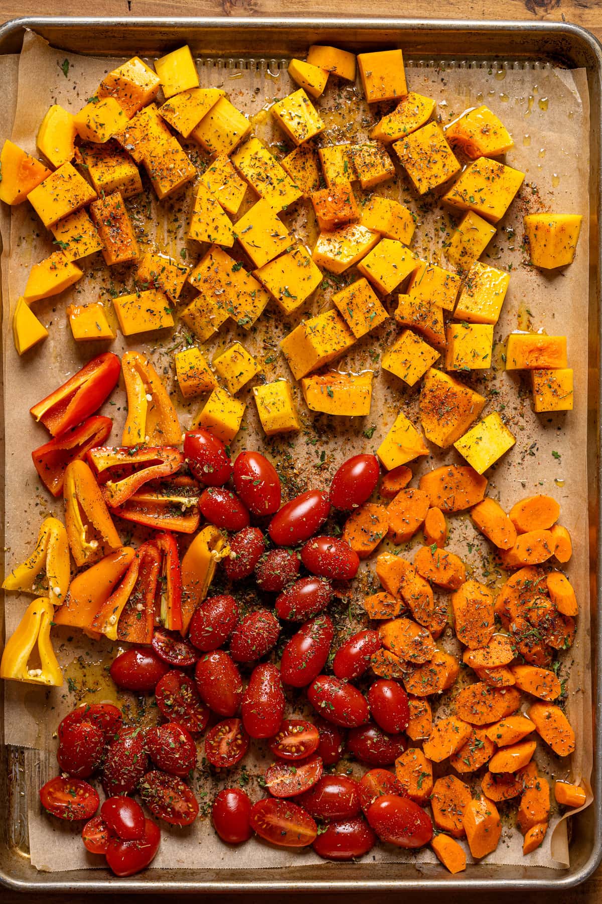 Sheet pan of seasoned butternut squash, carrots, peppers, and grape tomatoes