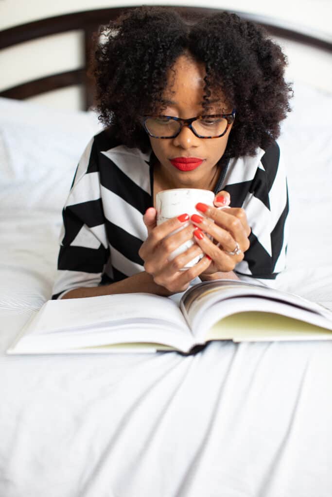 Shanika holding a mug and reading a book.