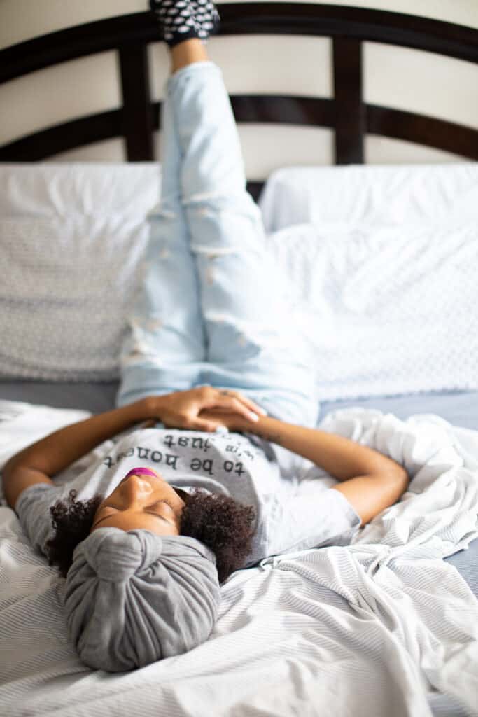 Shanika lying on a bed with her feet elevated on the headboard.