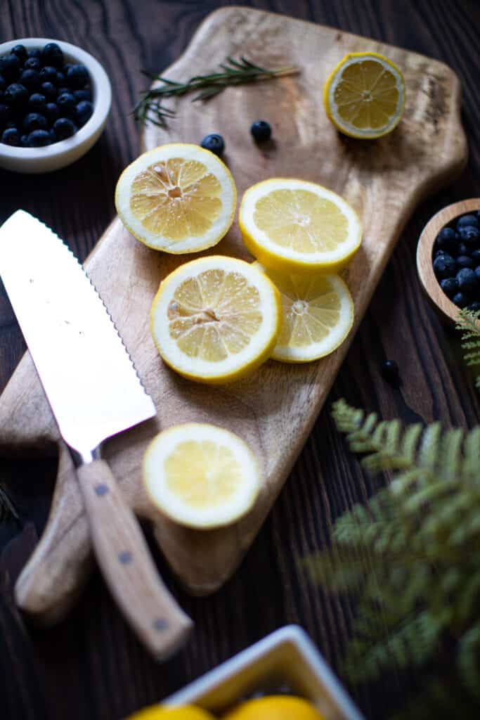 Lemon slices on a wooden board with a knife.