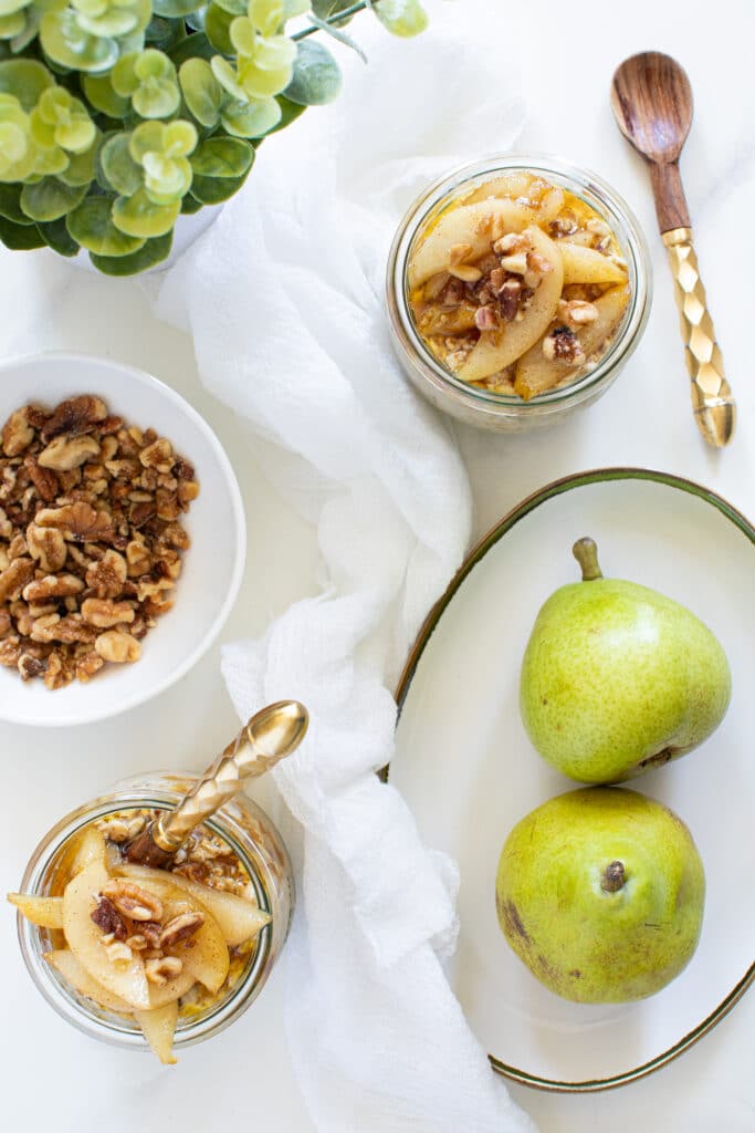 Vanilla Overnight Oats with Maple Spiced Pears on a table with pears.