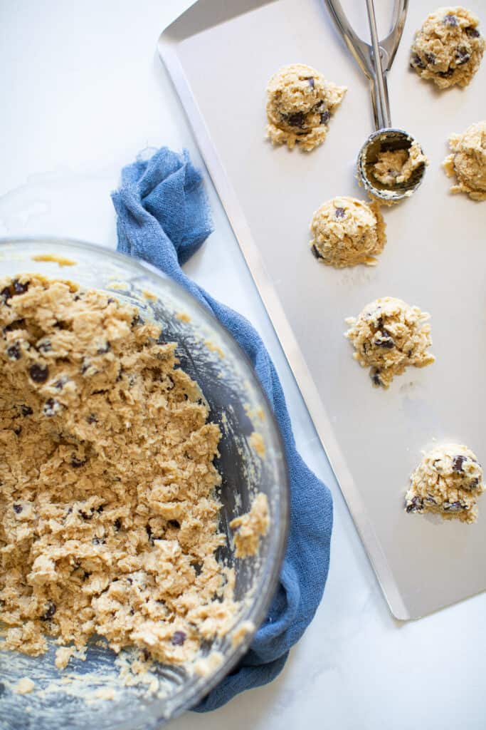 Balls of Peanut Butter Oatmeal Chocolate Chip Cookie dough on a baking sheet.