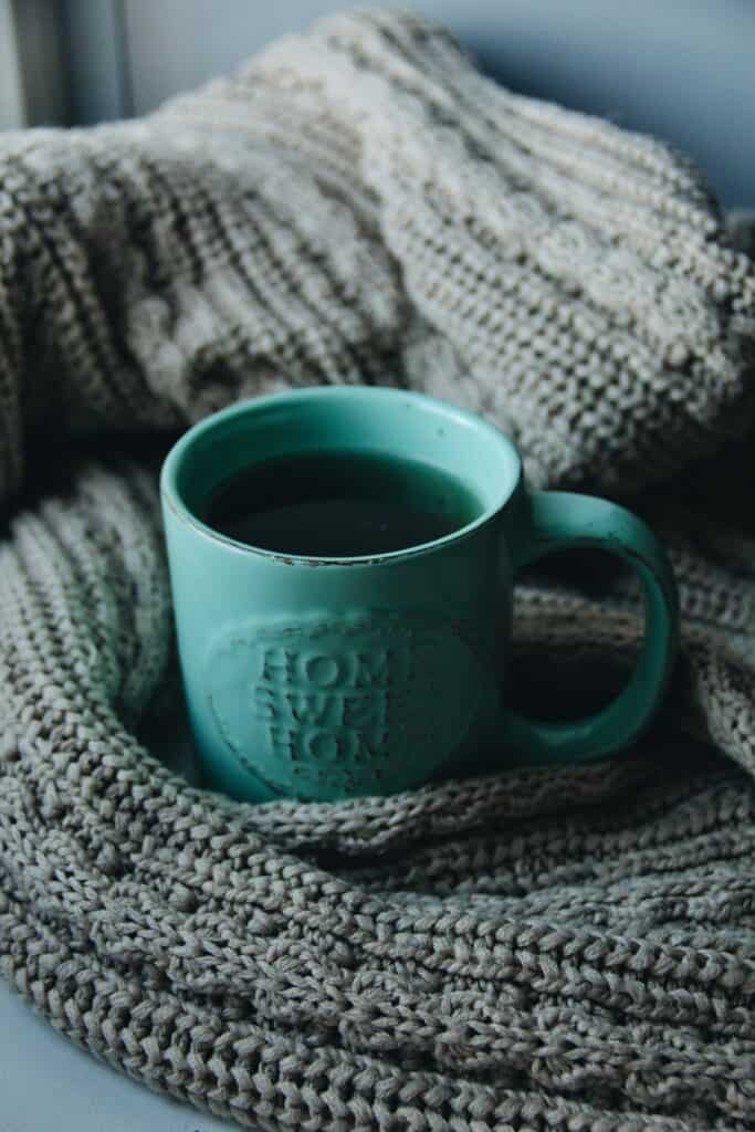 Mug that reads \"Home Sweet Home\" wrapped in a knit fabric.