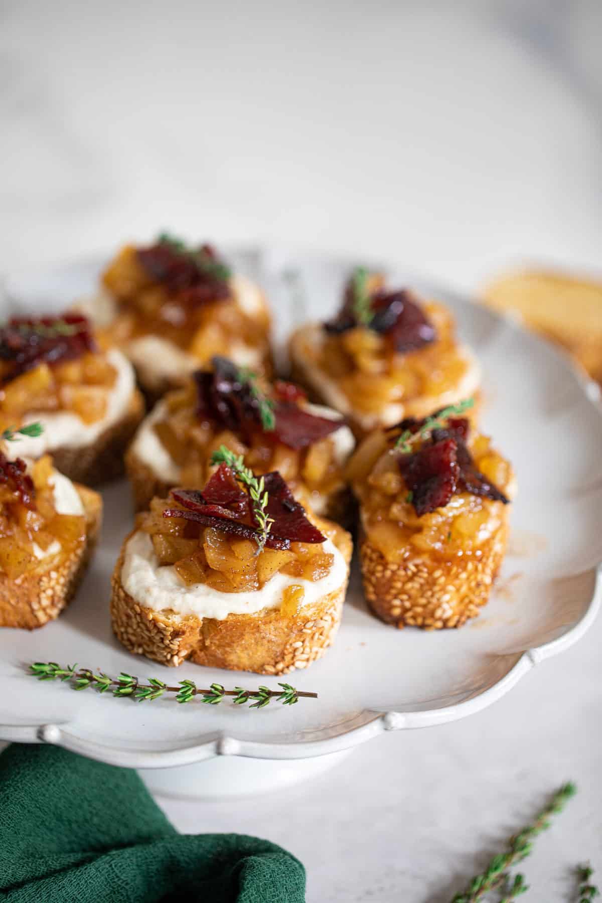 Fall Harvest Apple Bacon Crostini on a platter with a sprig of thyme.