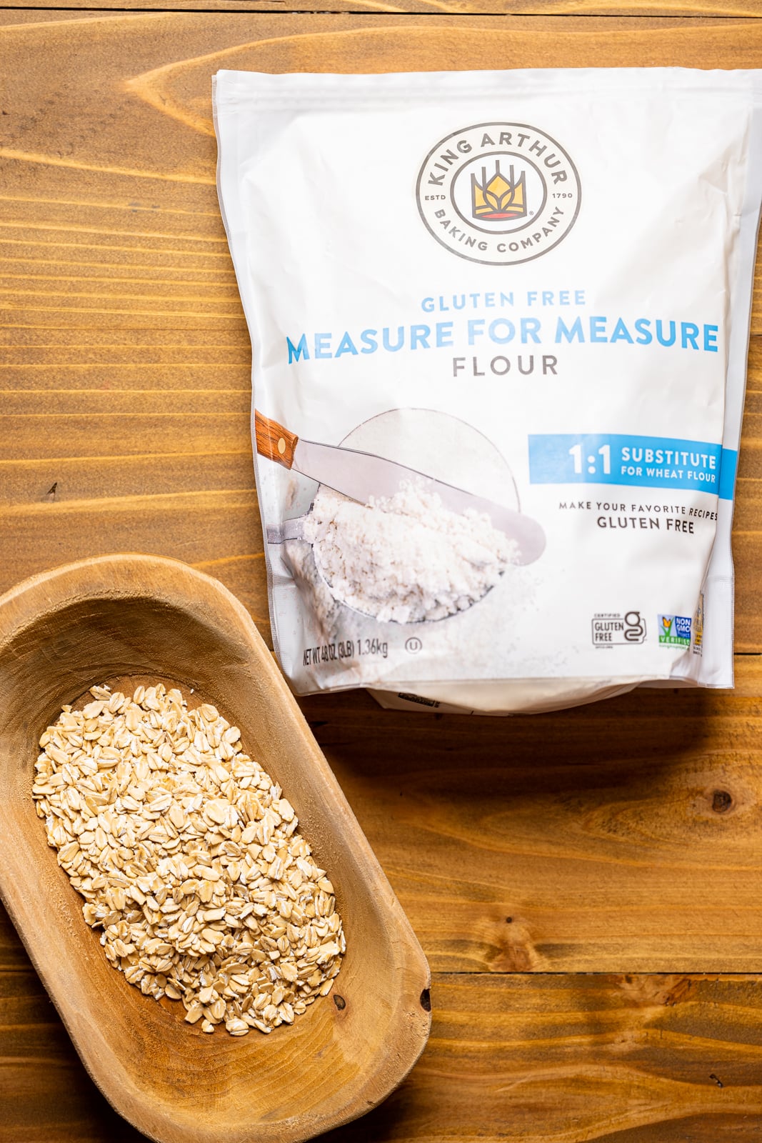 Gluten-free flour and oats on a brown wood table.