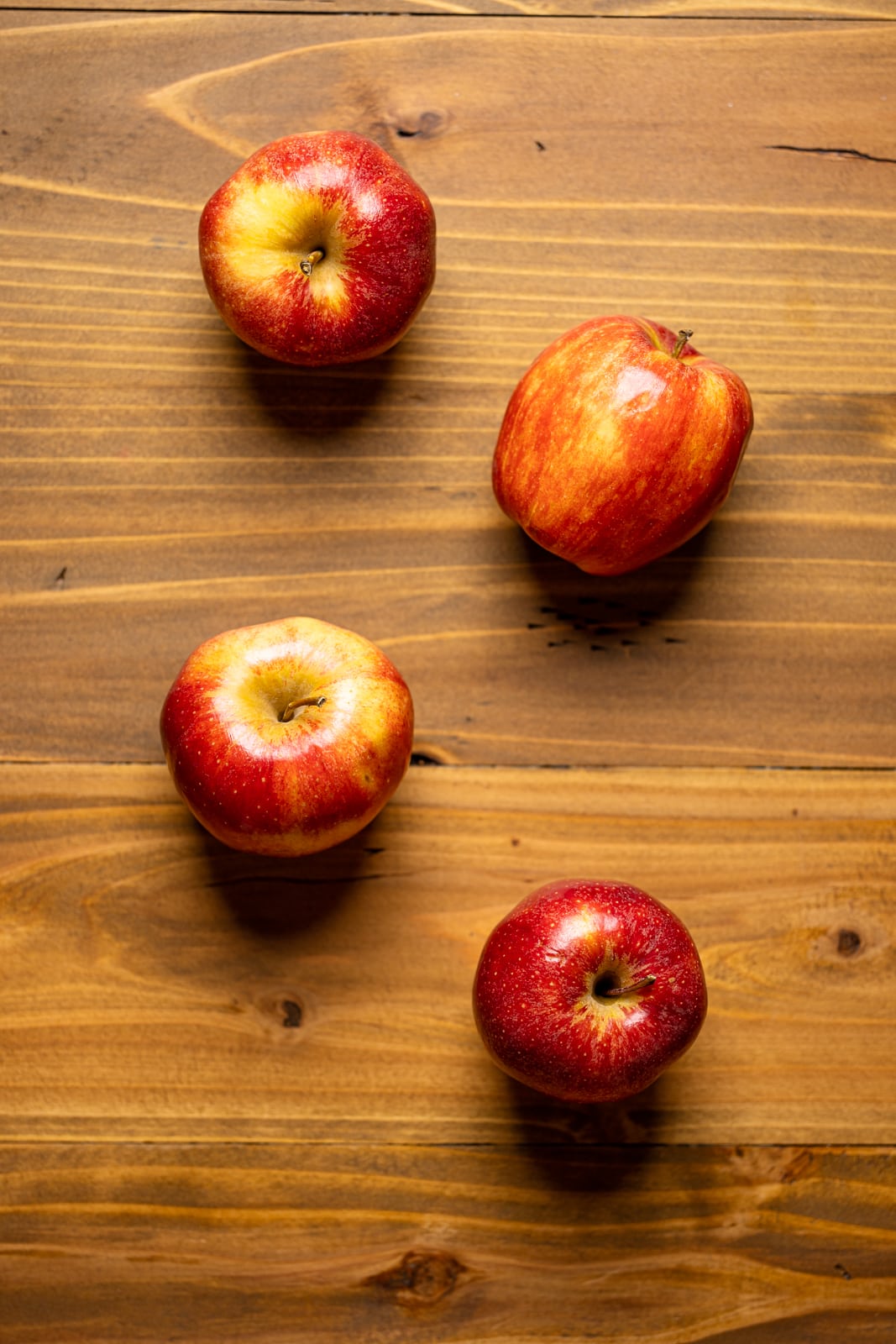 Red apples on a brown wood table.