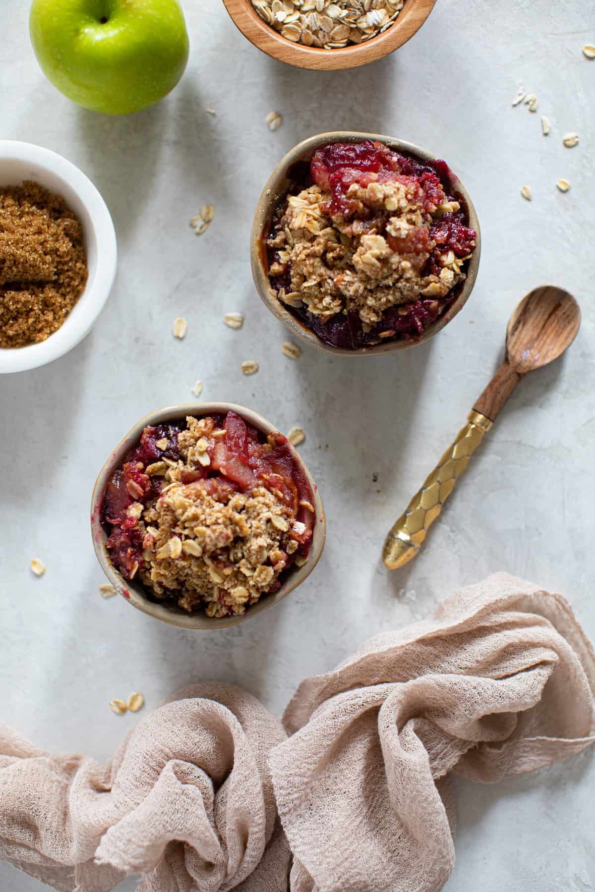 Two small bowls of Vegan and Gluten-Free Apple Plum Crisp with a spoon.