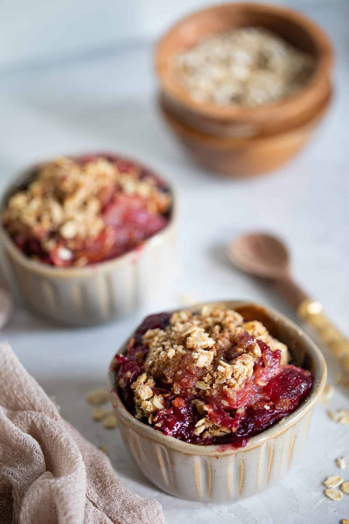 Spoon next to two small bowls of Vegan and Gluten-Free Apple Plum Crisp.