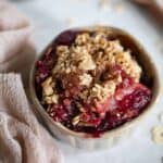 Vegan and Gluten-Free Apple Plum Crisp in a small bowl with a cloth napkin.