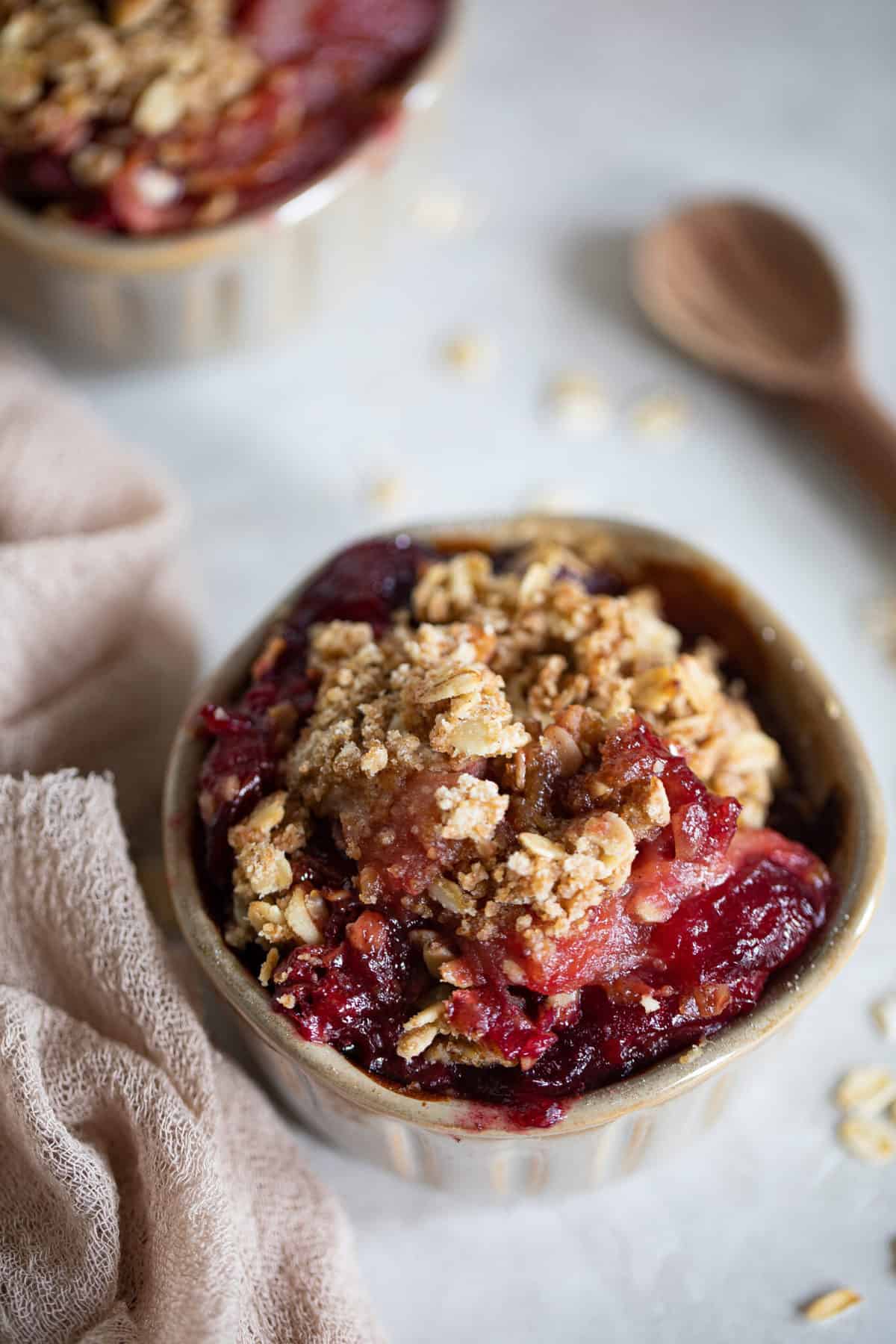 Vegan and Gluten-Free Apple Plum Crisp in a small bowl with a cloth napkin.