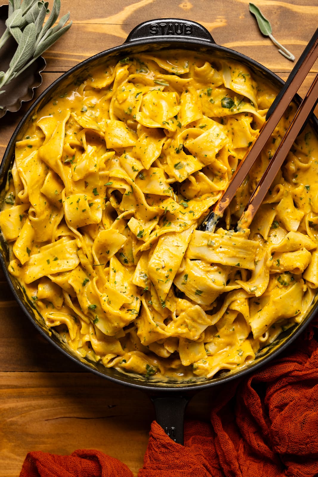 Creamy pasta in a black skillet with tongs. 