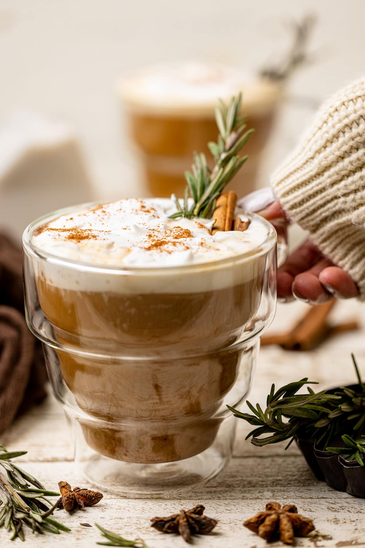 Woman grabbing a glass mug of Vegan Pumpkin Chai Latte.