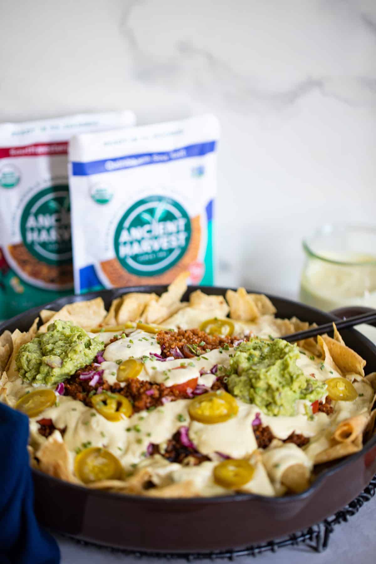 Black Bean and Quinoa Skillet Nachos next to bags of Ancient Harvest quinoa.