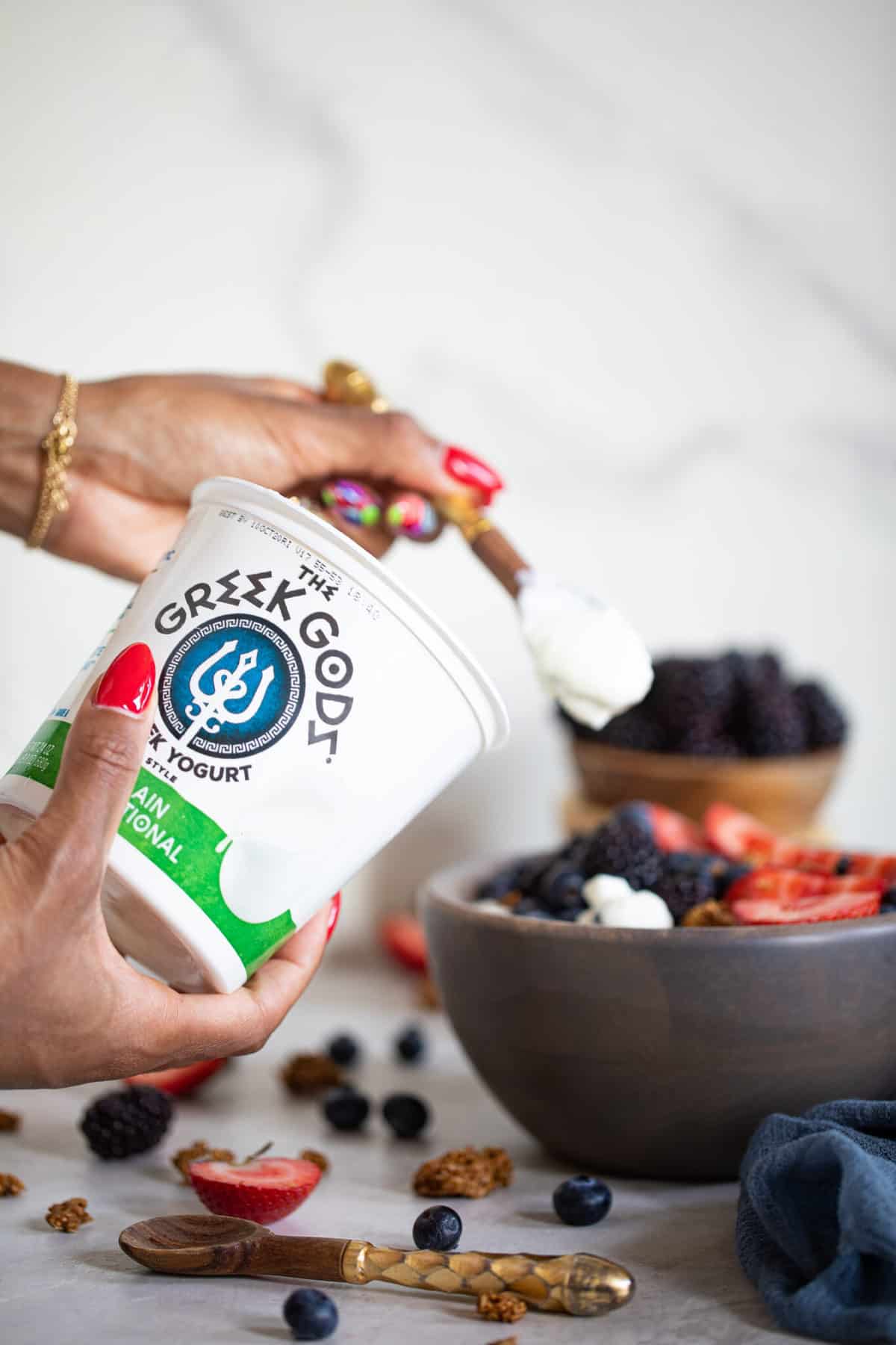 Woman scooping Greek Gods yogurt into a Greek Yogurt Breakfast Bowl.