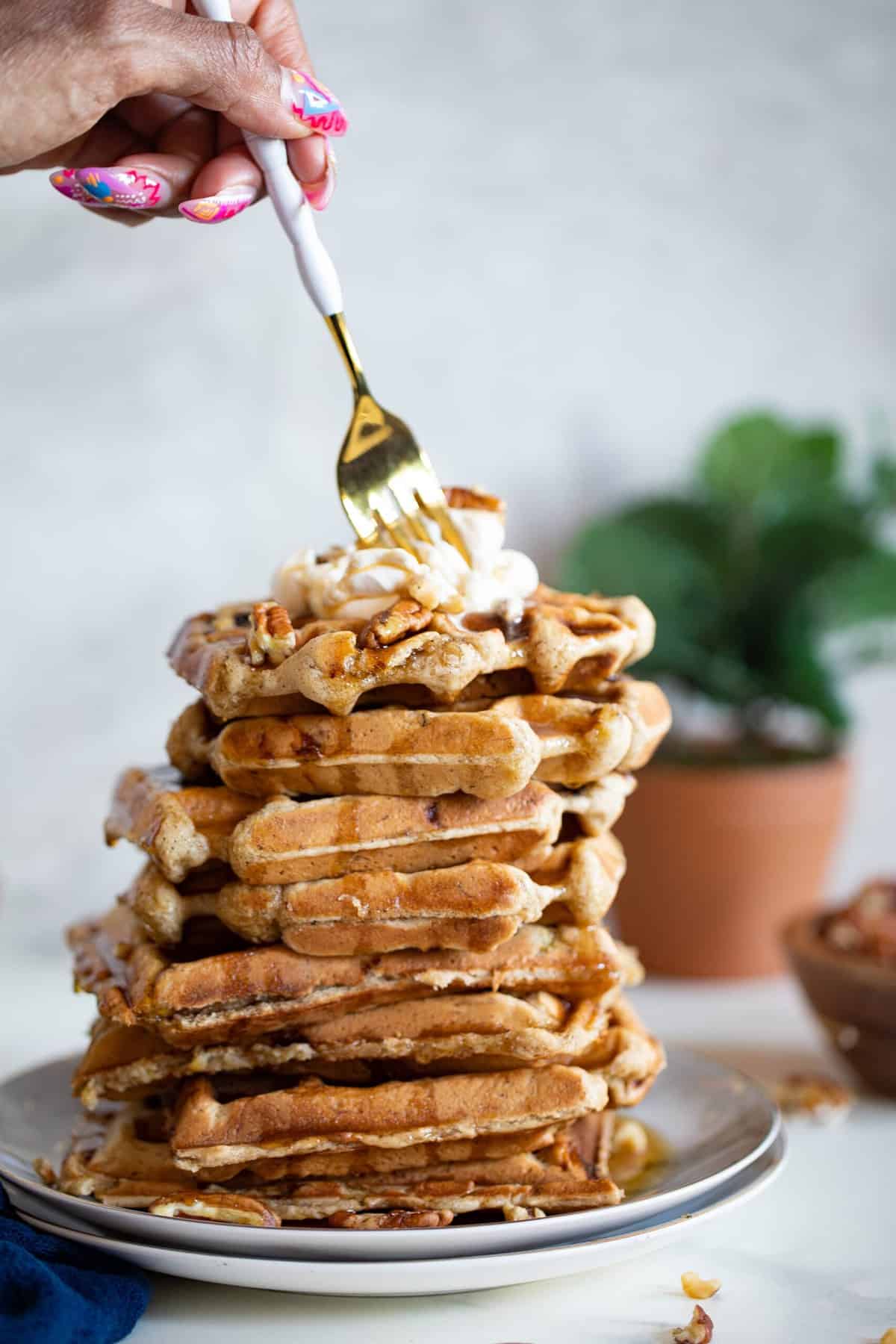 Fork grabbing from a stack of Maple Brown Butter Banana Waffles.