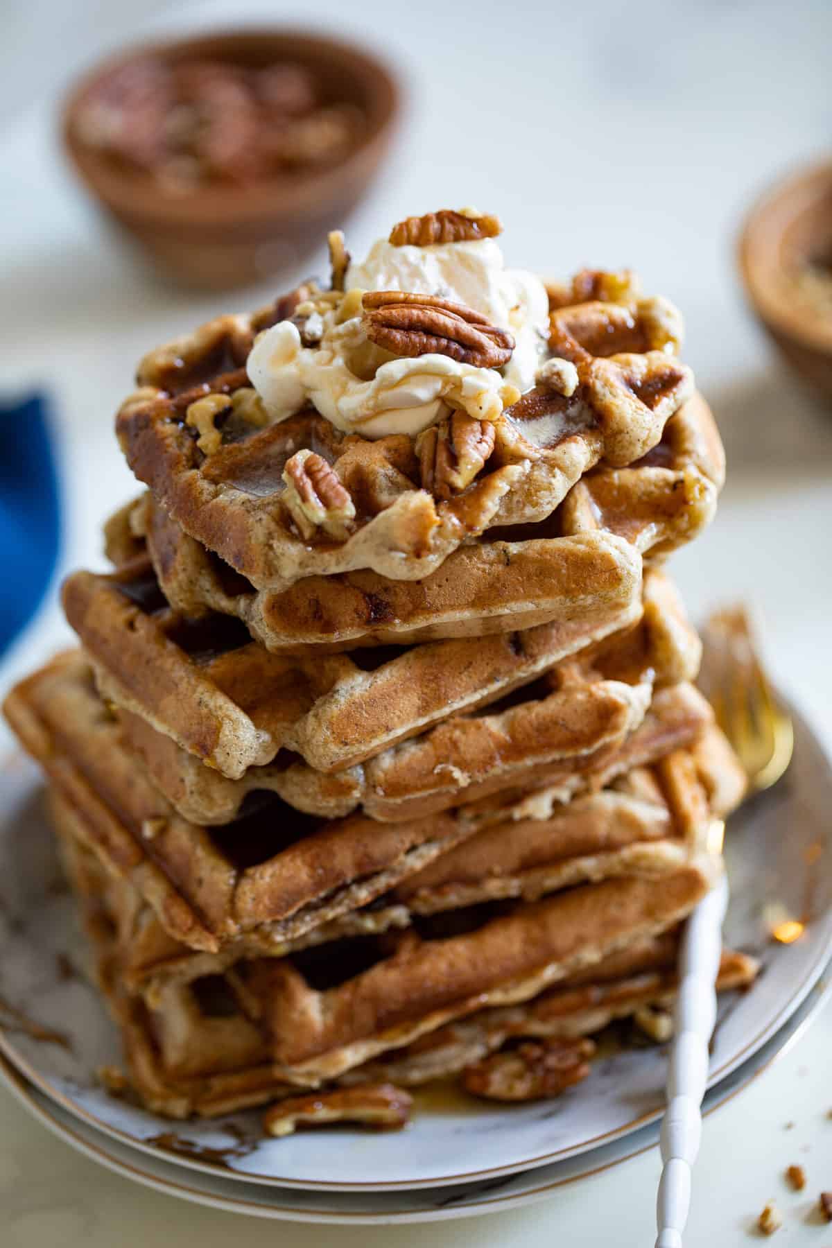 Maple Brown Butter Banana Waffles topped with nuts and syrup.