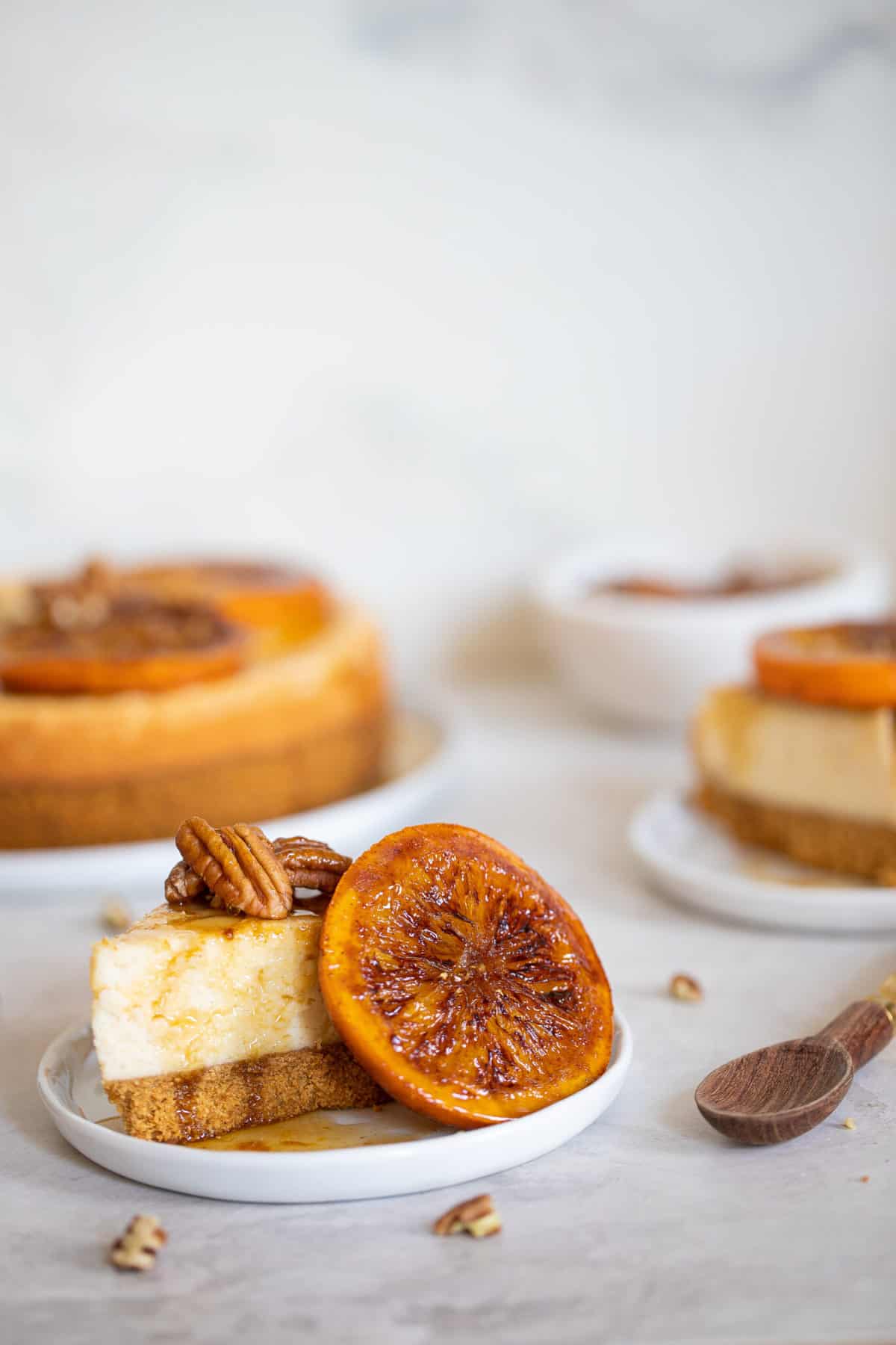 Slices of Spiced Orange Cheesecake with Pecan Crust with sliced oranges and pecans.