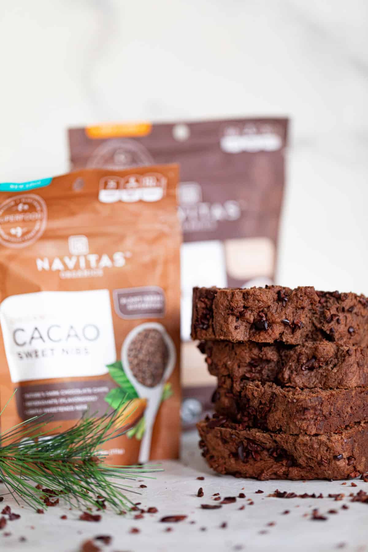 Slices of Vegan Chocolate Bread piled next to a bag of Navitas Cacao sweet nibs.