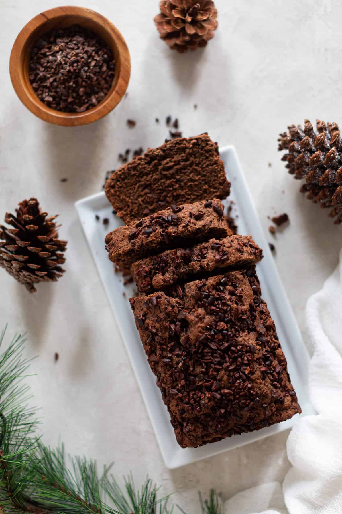 Partially-sliced loaf of Vegan Chocolate Bread on a white plate.