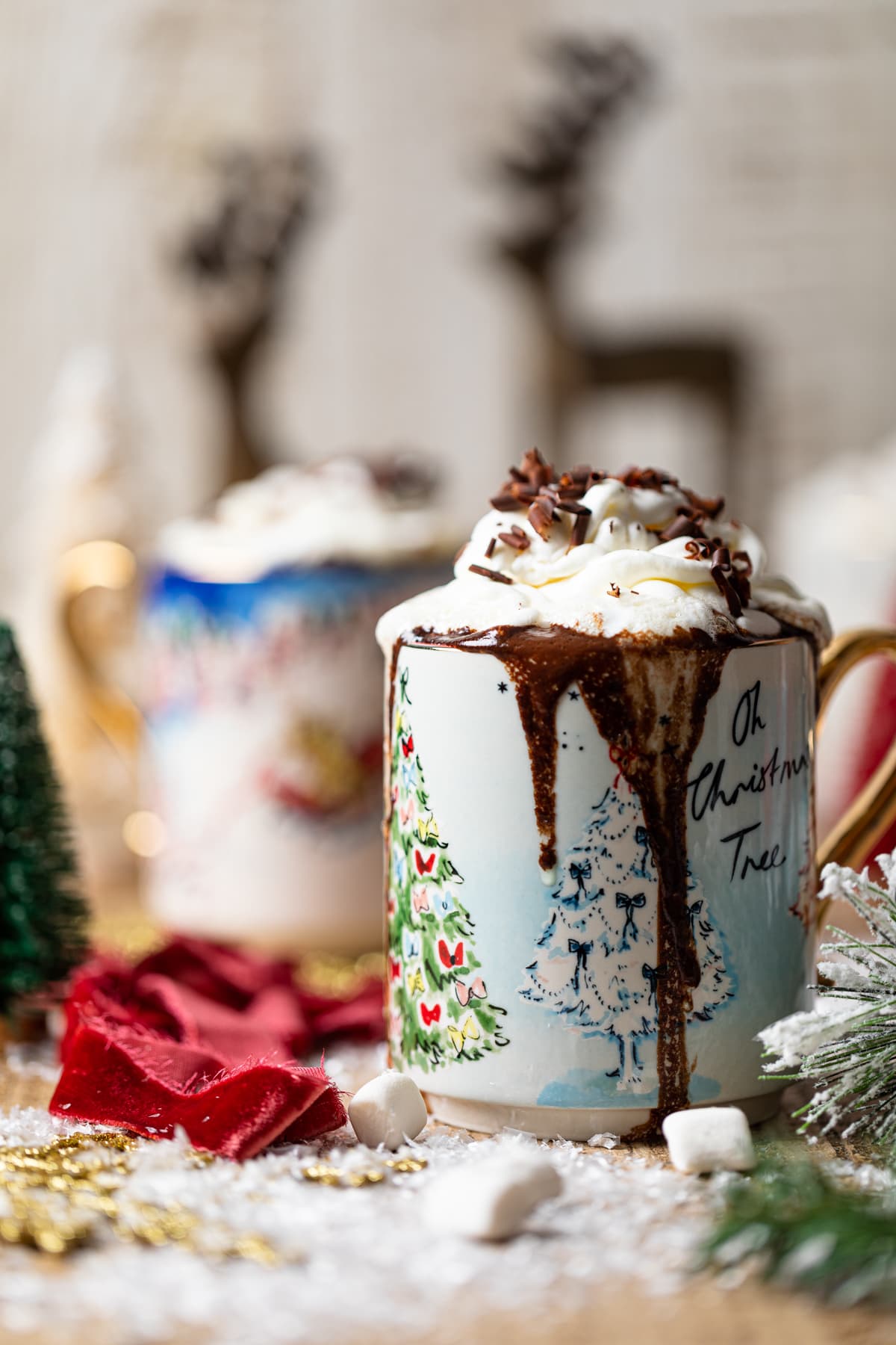 Mug with pictures of Christmas trees overflowing with Creamy Caramel Hot Chocolate