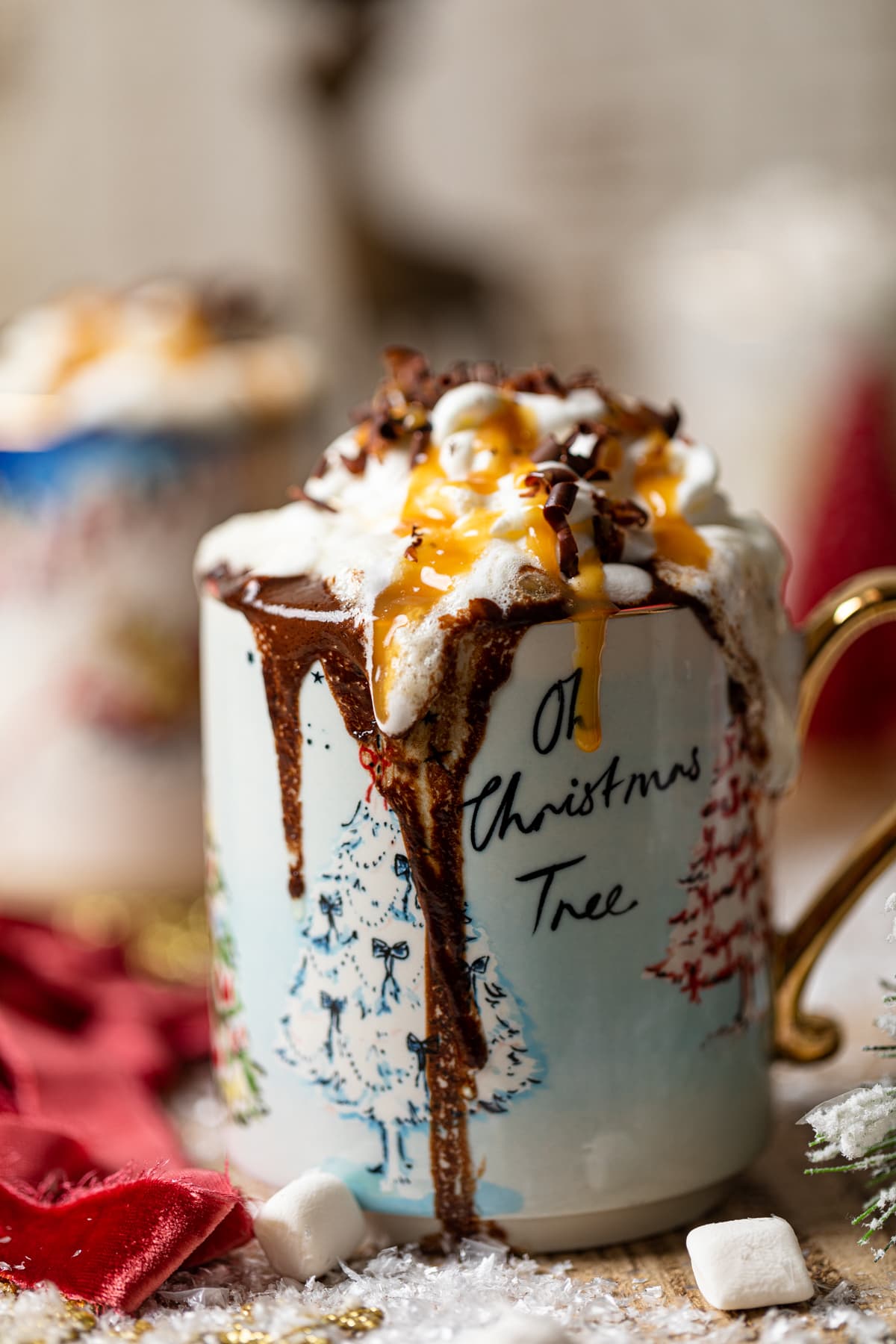 Creamy Caramel Hot Chocolate topped with coconut whipped cream, chocolate shavings, and caramel sauce