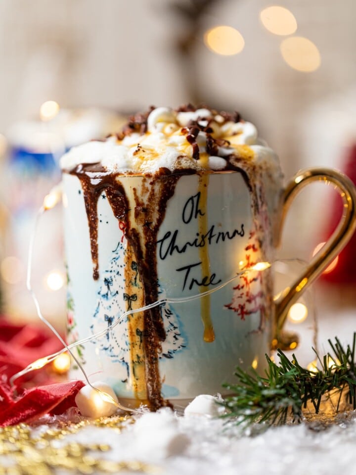 Creamy Caramel Hot Chocolate overflowing a Christmas mug