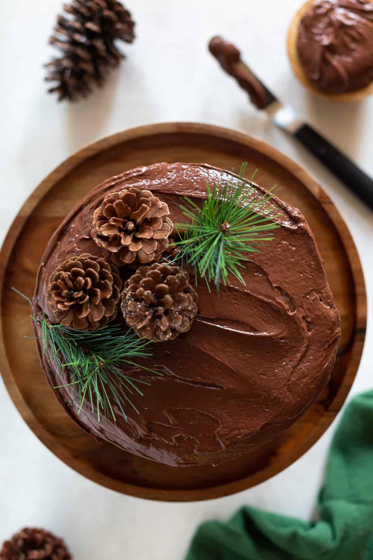 Vegan Brownie Cookie Dough Cake topped with pinecones and evergreen sprigs.