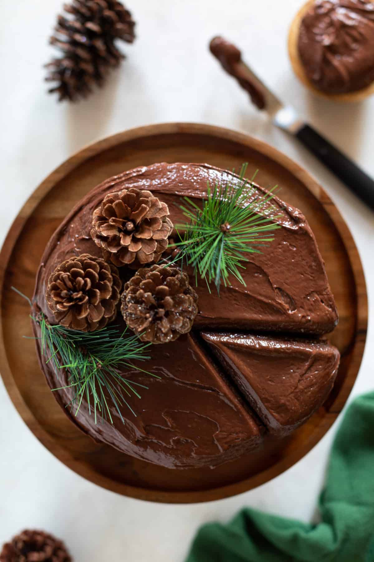 Pinecones and evergreen sprigs on a Vegan Brownie Cookie Dough Cake.