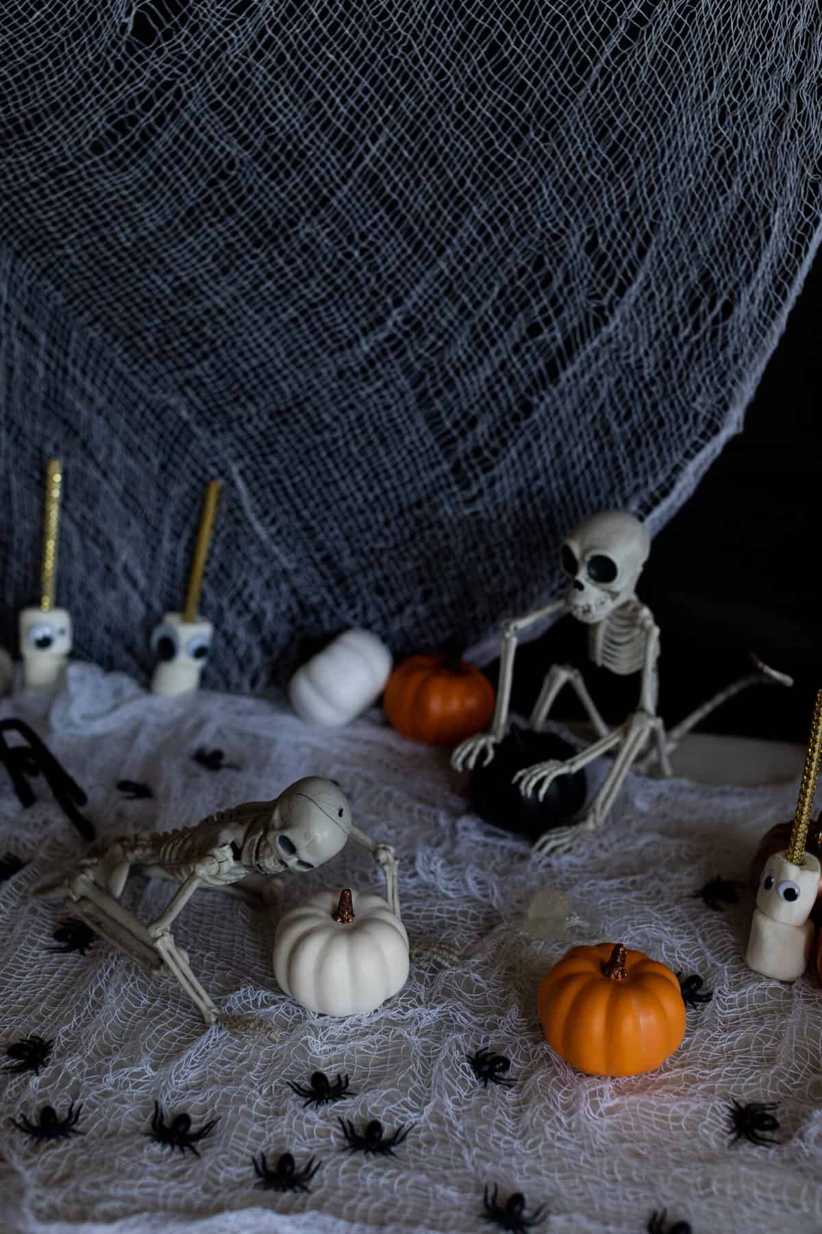 Skeletons, pumpkins, and spiders on a table.